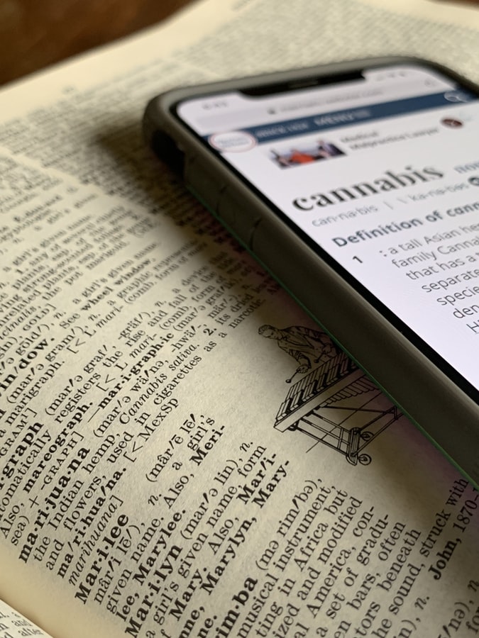 A cell phone and a dictionary flipped to the page that defines marijuana